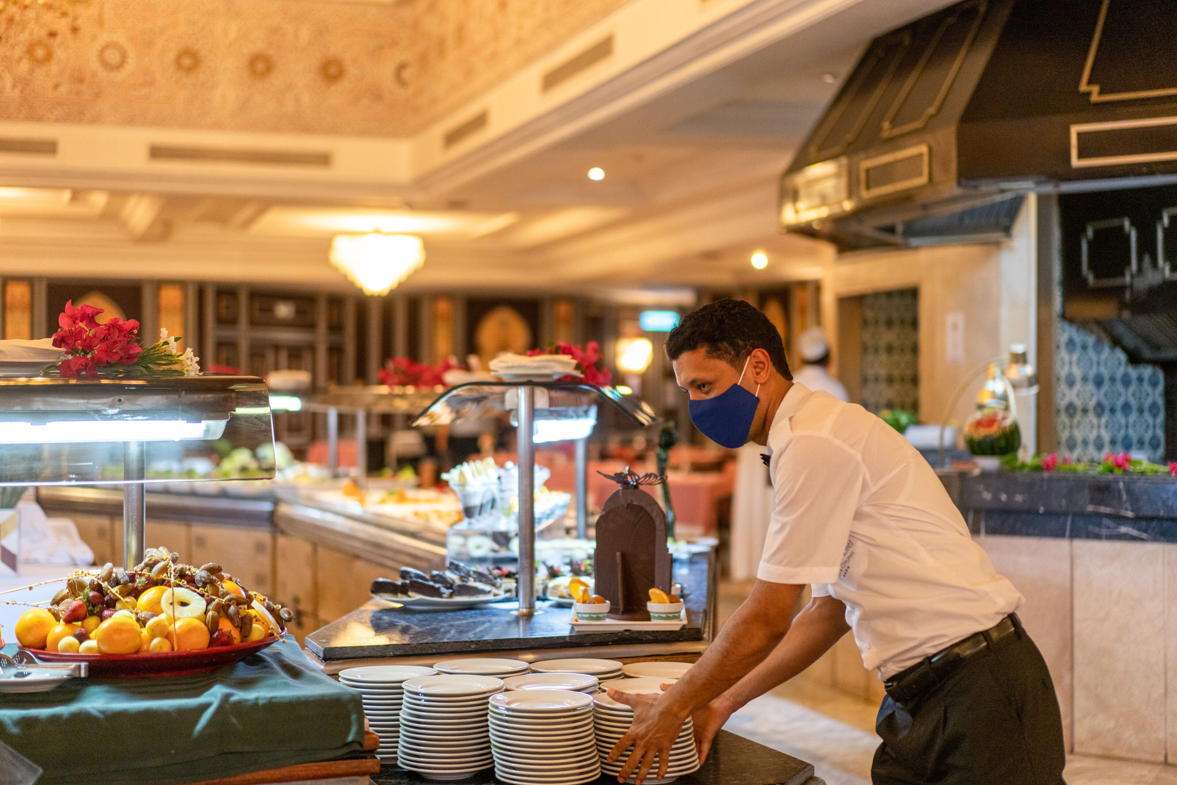 A buffet setup with various food items and a person serving.