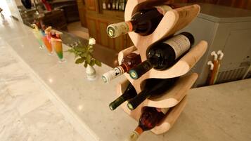 A wine rack with multiple bottles and a row of colorful drinks on a marble countertop.