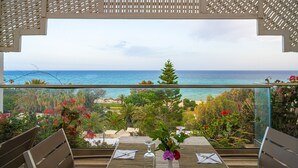 Un balcón con mesa lista para comer, con vista a la playa y al océano.