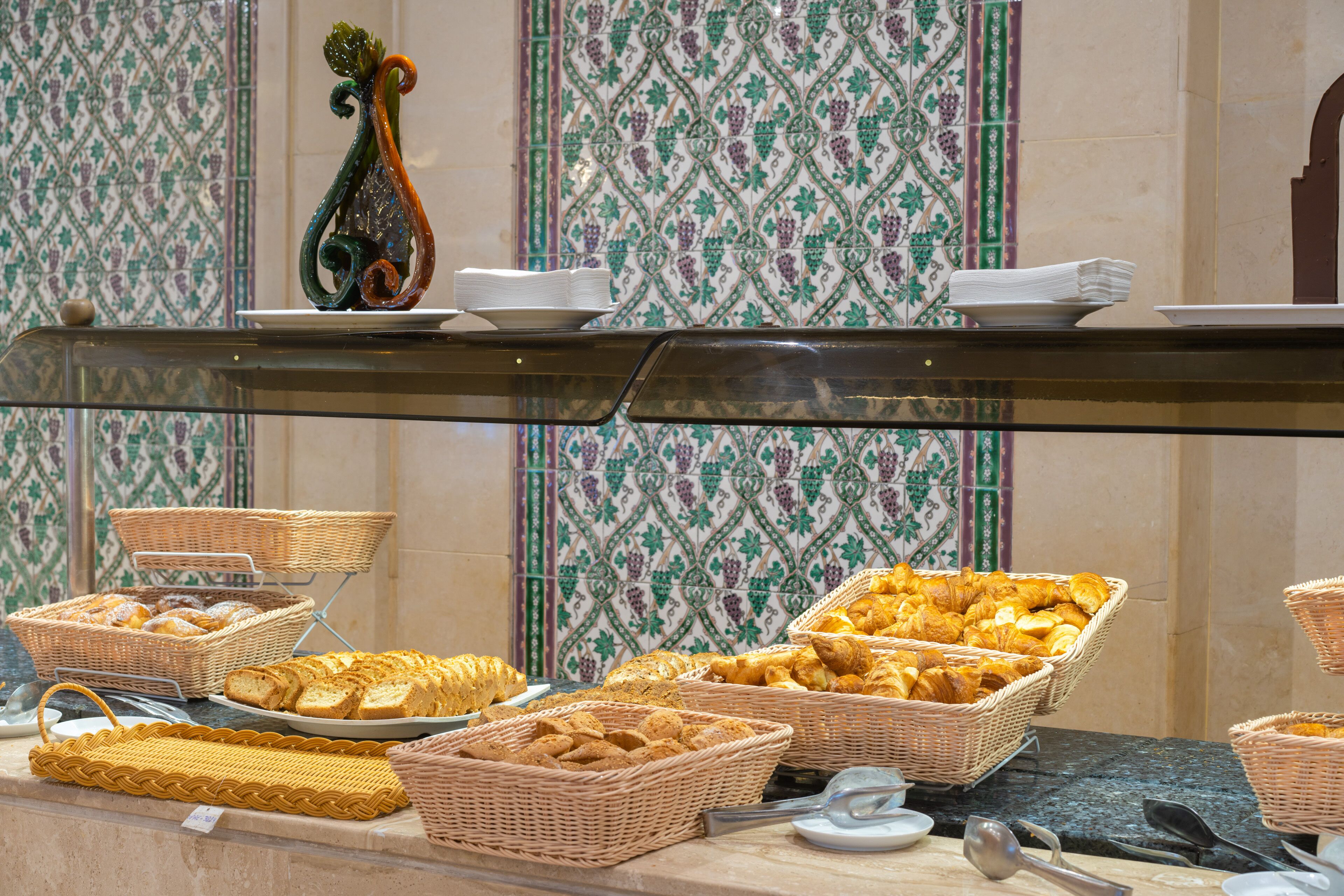 A buffet with various baked goods and bread baskets.