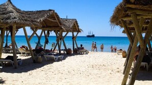 A beach with wooden huts and lounge chairs. - The Orangers Beach Resort and Bungalows - All Inclusive (Hammamet)