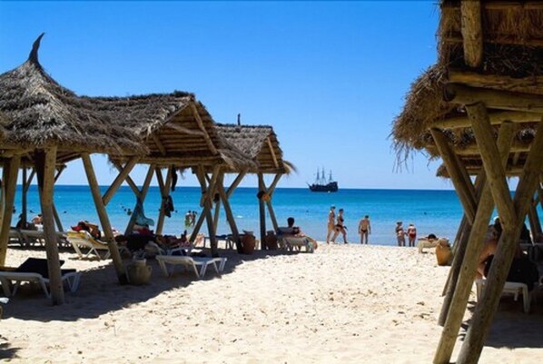 Aan een privéstrand, wit zand, ligstoelen, parasols