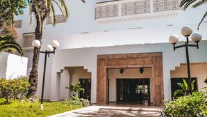 A building entrance with a stone pathway, palm trees, and a decorative light fixture. - The Orangers Beach Resort and Bungalows - All Inclusive (Hammamet)