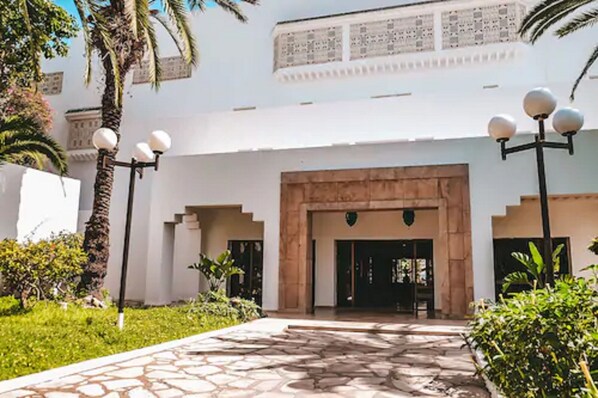 A building entrance with a stone pathway, palm trees, and a decorative light fixture. - The Orangers Beach Resort and Bungalows - All Inclusive (Hammamet)