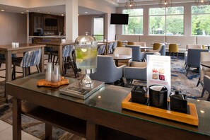 A hotel lobby with a bar area, seating arrangements, and a large window providing a view of the outdoors.