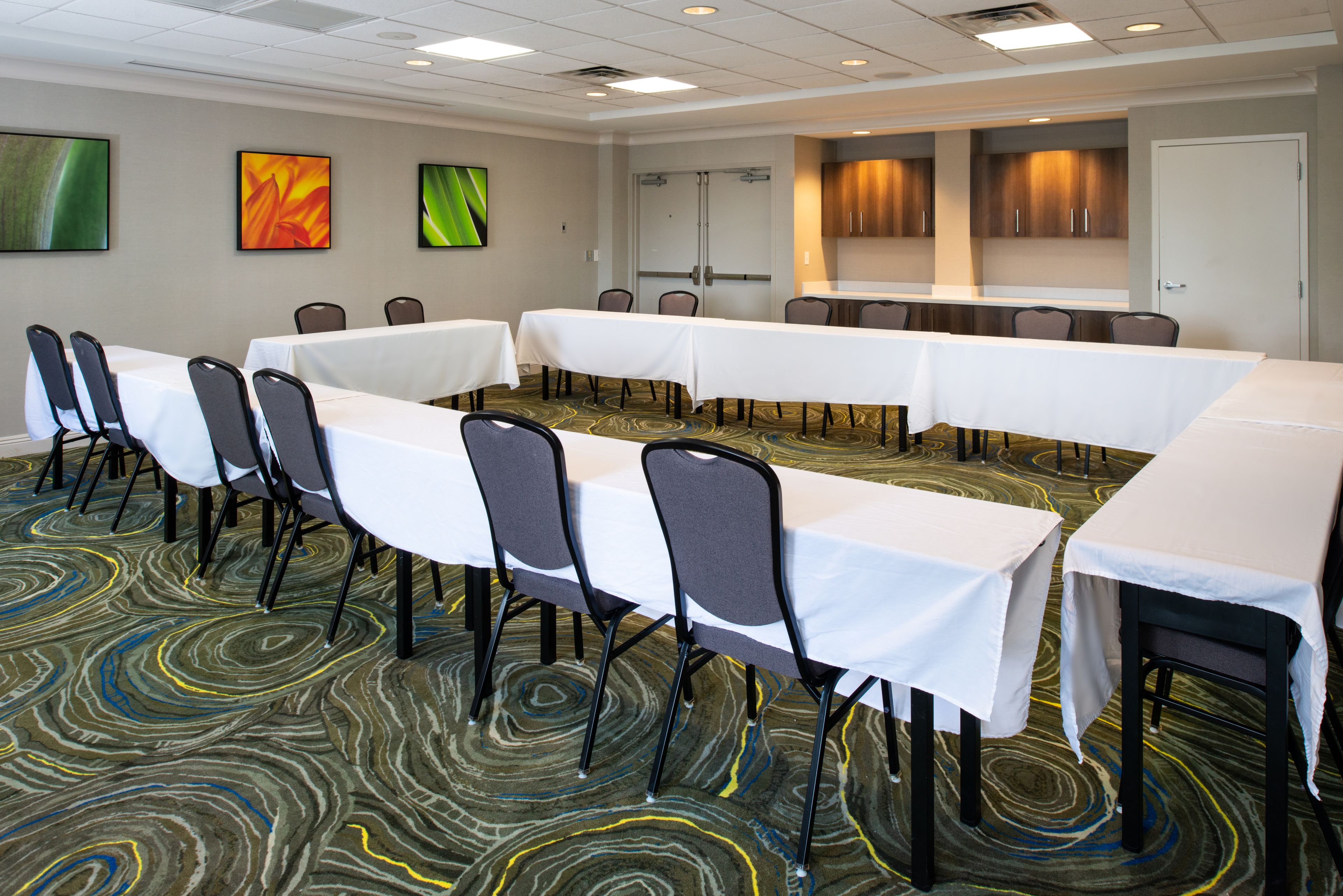 A conference room with a long table, multiple chairs, and a carpeted floor.