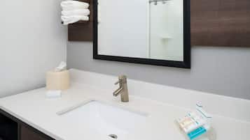 Un baño con lavamanos blanco, un espejo y un perchero para toallas.