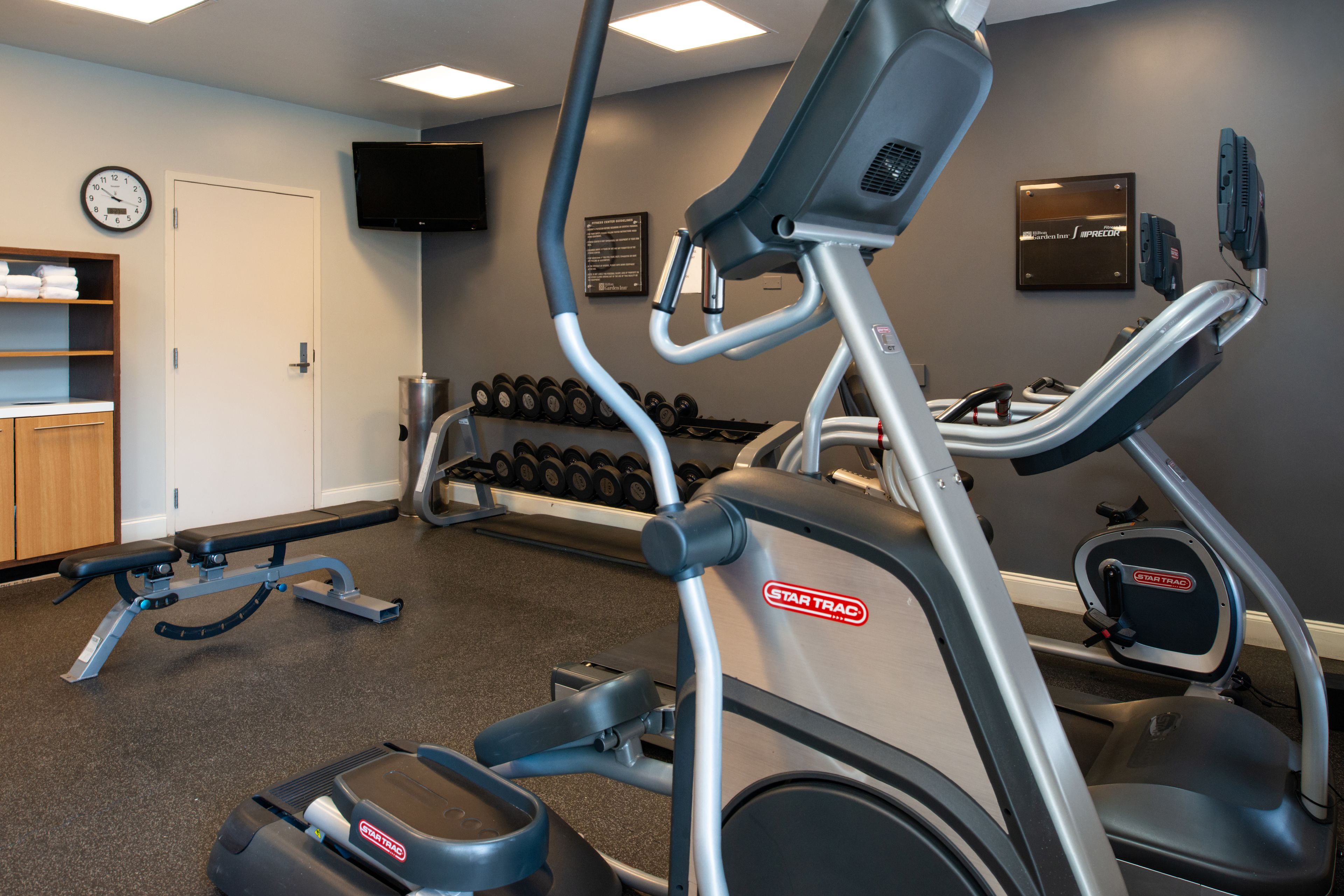 Une salle de sport équipée de tapis de course, d’haltères et d’un banc de musculation.