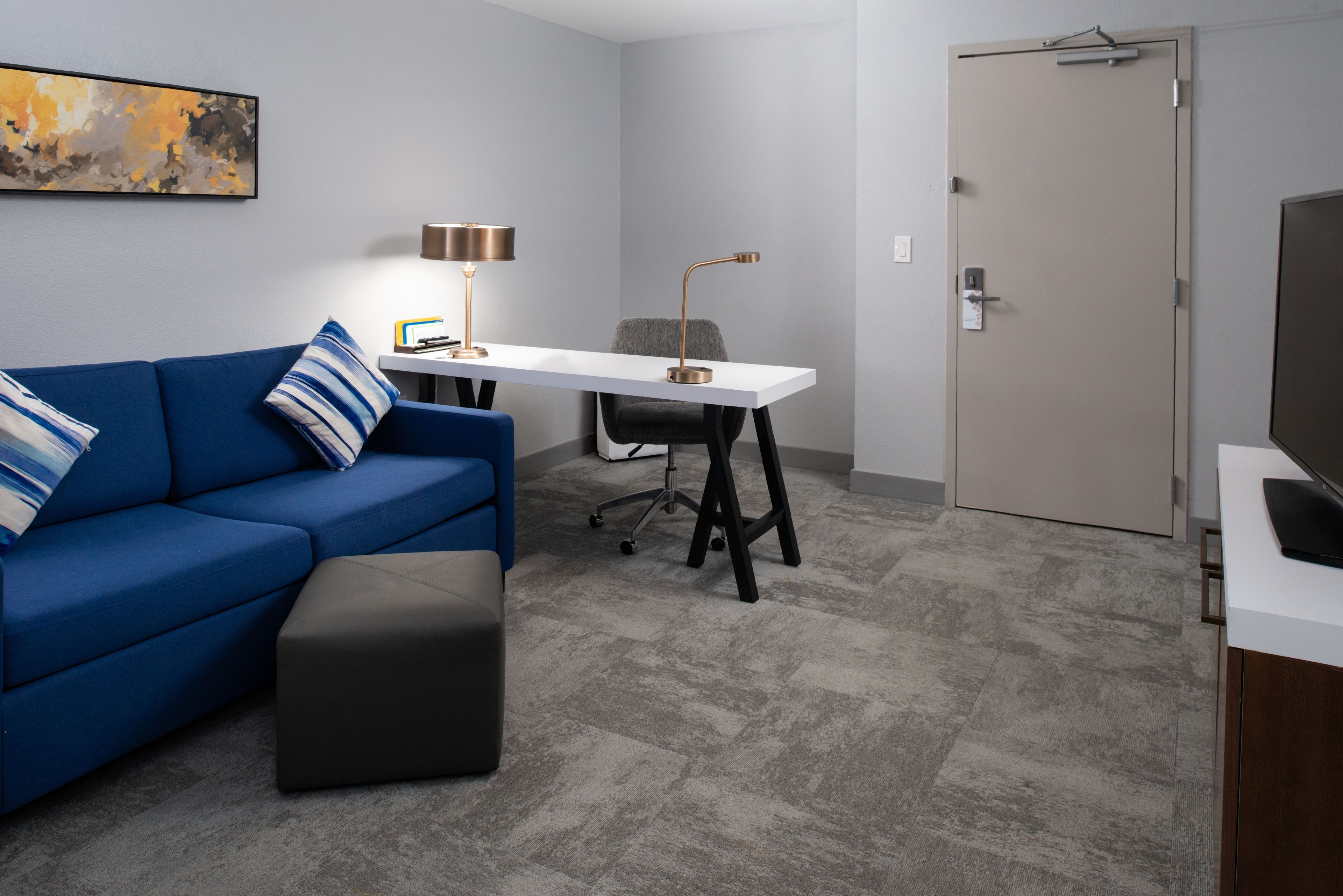 A modern room with a blue sofa, a white desk, and a closed door.