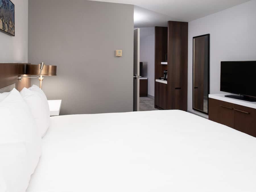 A hotel room with a large bed, a bedside table, a lamp, a TV, and a wardrobe.