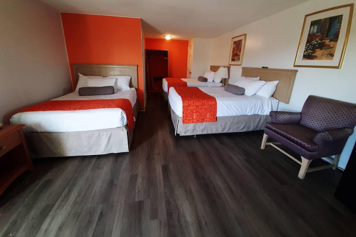 A hotel room with two beds, a sofa, and a painting on the wall.