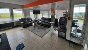A modern waiting area with leather sofas, a flat-screen TV, and a self-service kiosk. - Howard Johnson by Wyndham Woodstock NB (Woodstock)