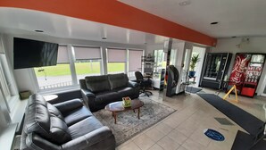 A spacious living area with a black leather sofa, a coffee table, and a flat-screen TV mounted on the wall. - Howard Johnson by Wyndham Woodstock NB (Woodstock)