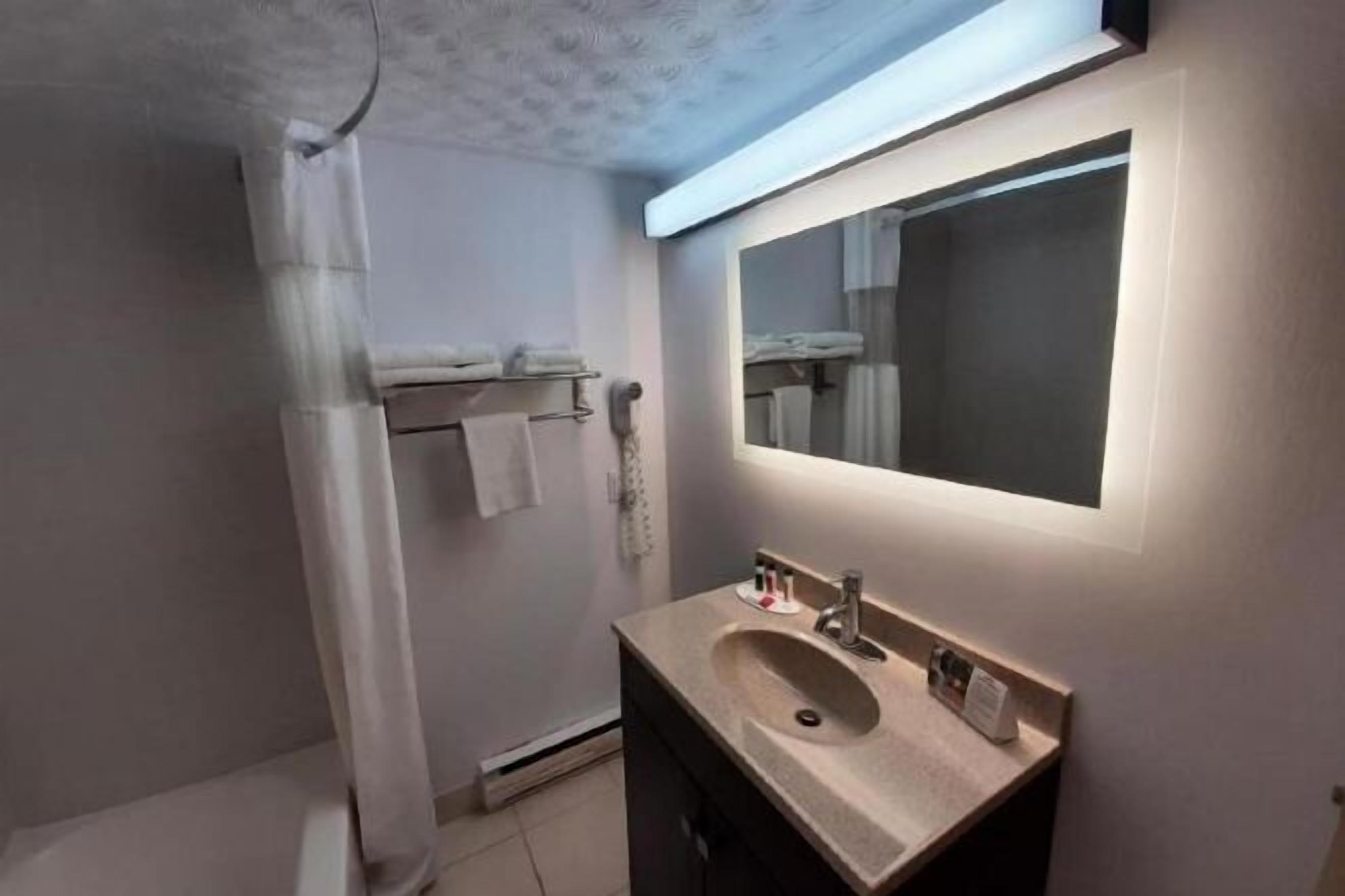 Badkamer | Een bad/douchecombinatie, een haardroger, handdoeken