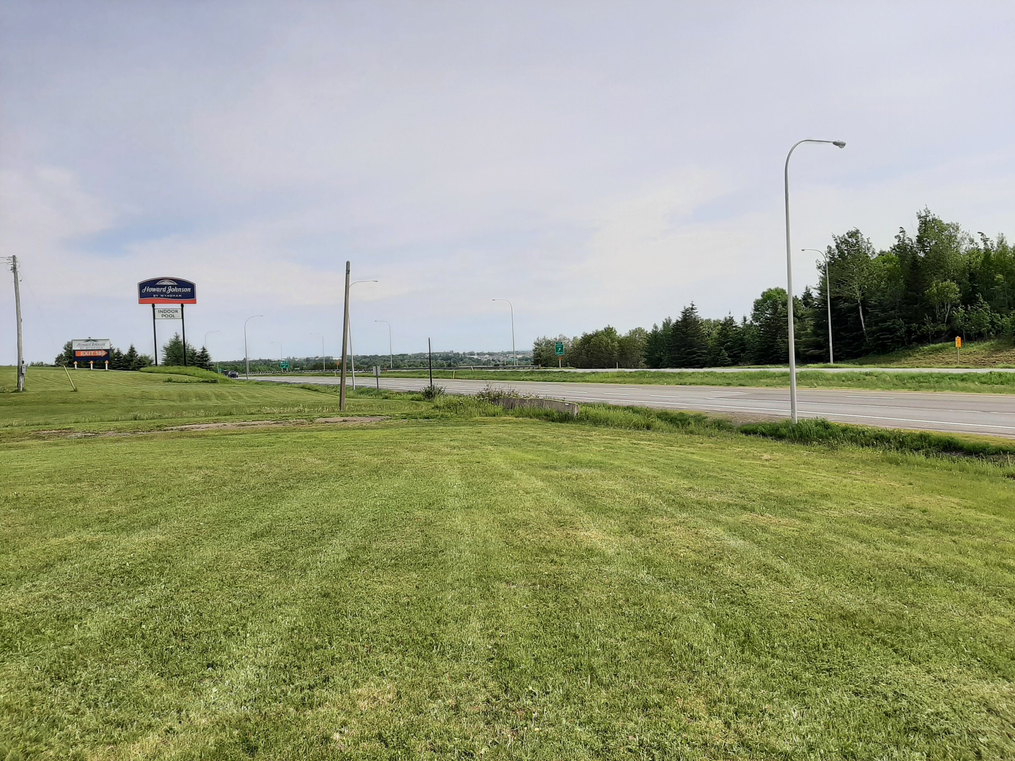 A grassy area with a road and a sign for Howard Johnson by Wyndham.