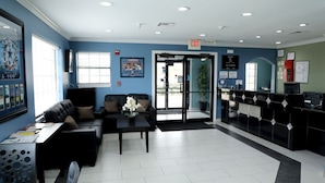 A reception area with a black reception desk, a seating area with a sofa and a coffee table, and a door leading outside.