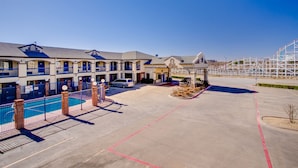 A hotel with multiple balconies, a swimming pool, and a parking area.