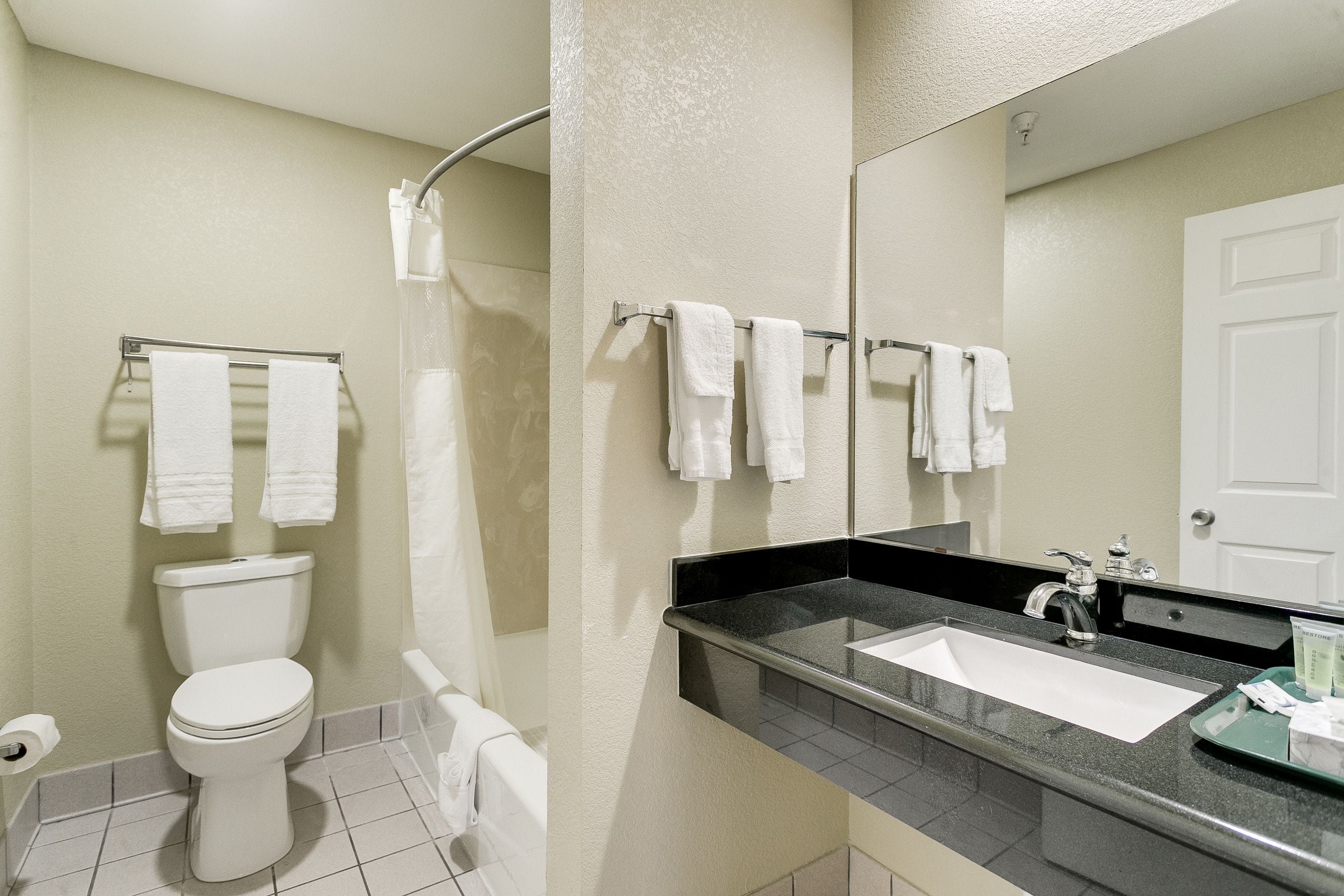A bathroom with a toilet, sink, and shower. There are towels hanging on a rack.