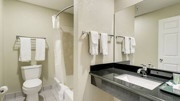 A bathroom with a toilet, sink, and shower. There are towels hanging on a rack.