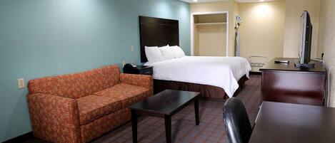 A hotel room with a bed, a sofa, a desk, and a chair.