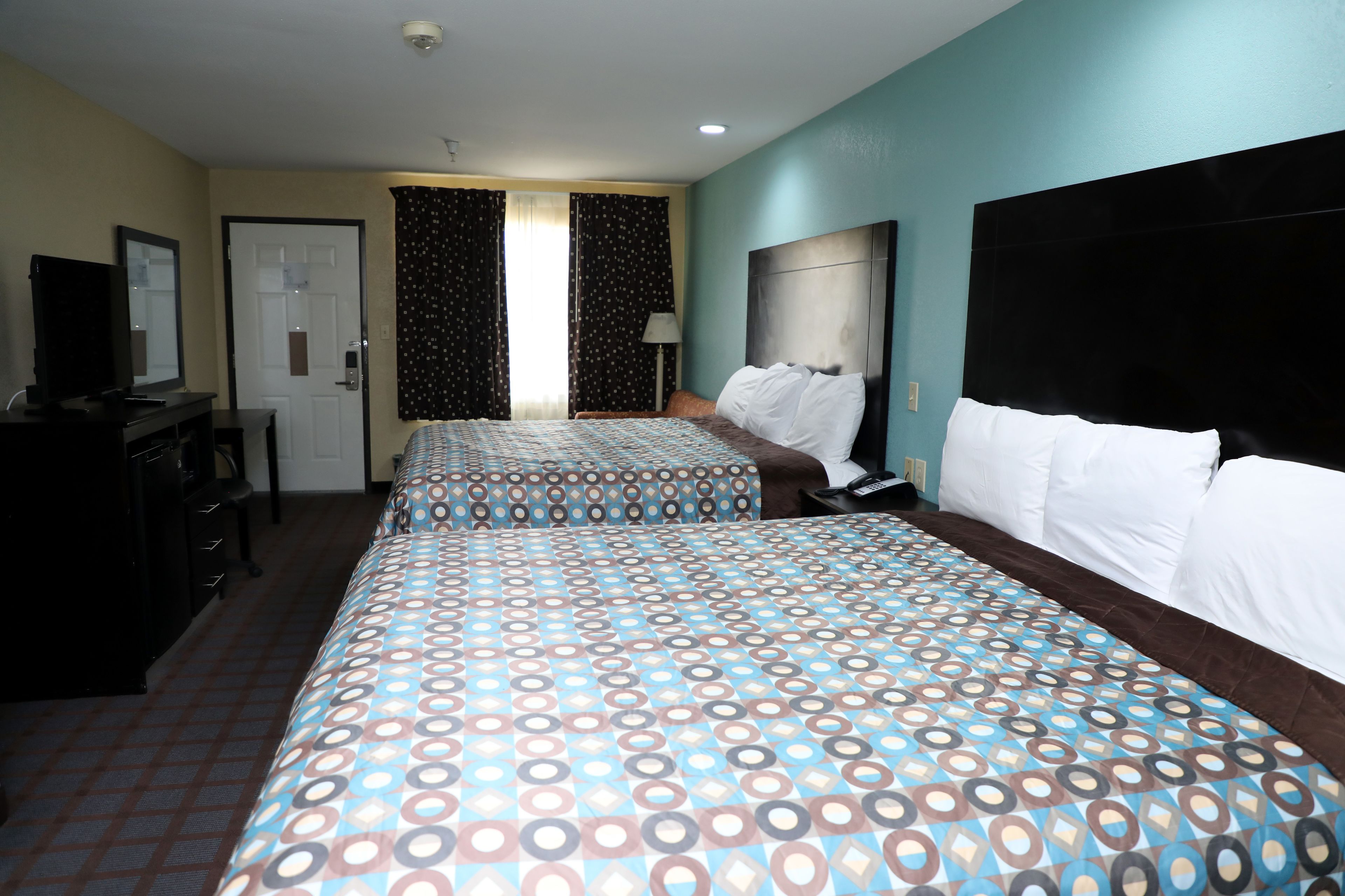 Une chambre d’hôtel avec deux lits, un bureau, une télévision et une porte.