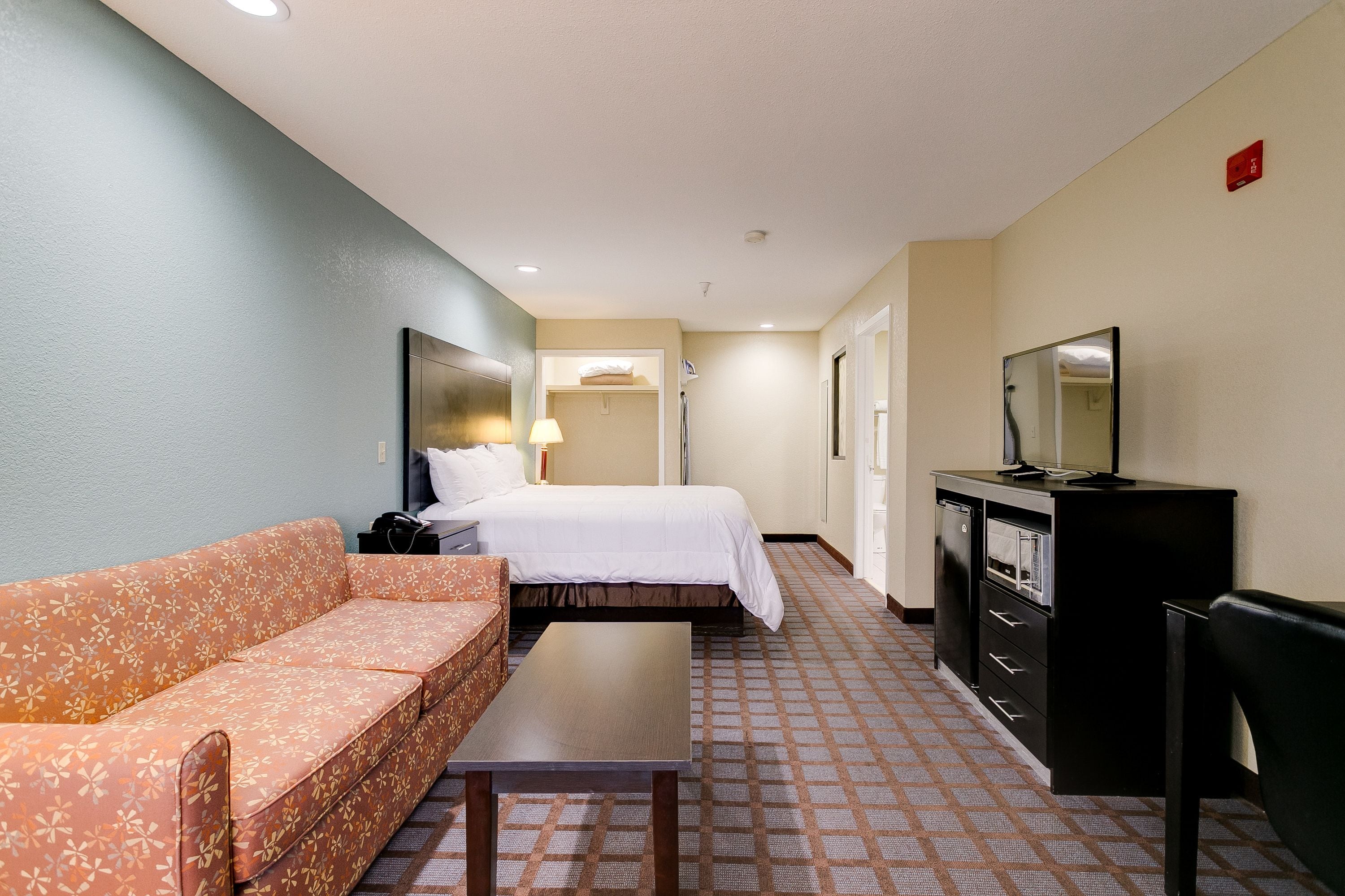 Une chambre d’hôtel comprenant un lit, un canapé, une télévision, un bureau et une armoire.