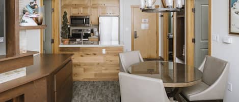 A modern kitchen with wooden cabinets, a central island, and a dining area with a glass table and chairs.