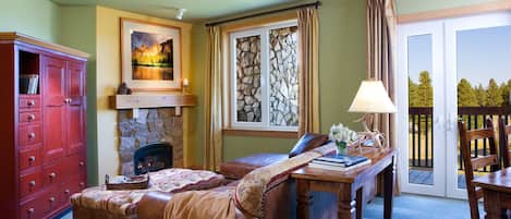 A cozy living room with a fireplace, a large window with curtains, a wooden table, and a red cabinet.