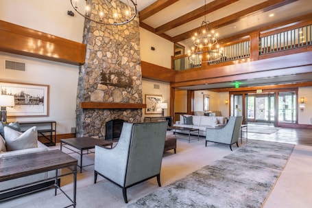 A spacious lobby with a stone fireplace, comfortable seating, and a balcony with wooden railings.. Juniper Springs Resort