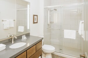 Een moderne badkamer met een grote spiegel, twee wastafels, een toilet en een douchecabine met glazen wanden.