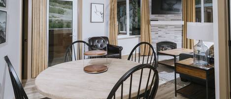Un comedor con una mesa redonda de madera, sillas negras y un sofá de cuero.