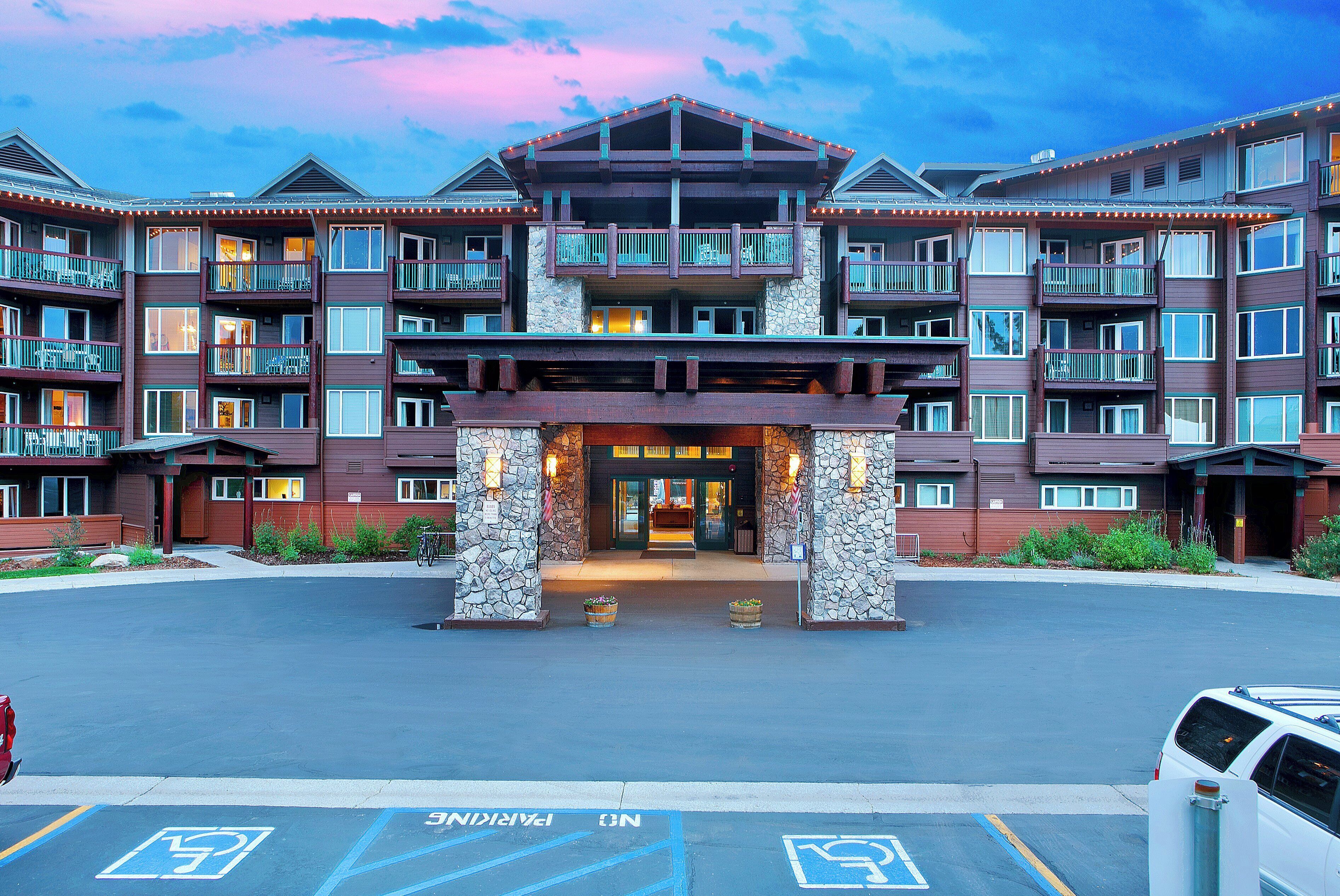 A multi-story hotel with a stone facade, balconies, and a central entrance.