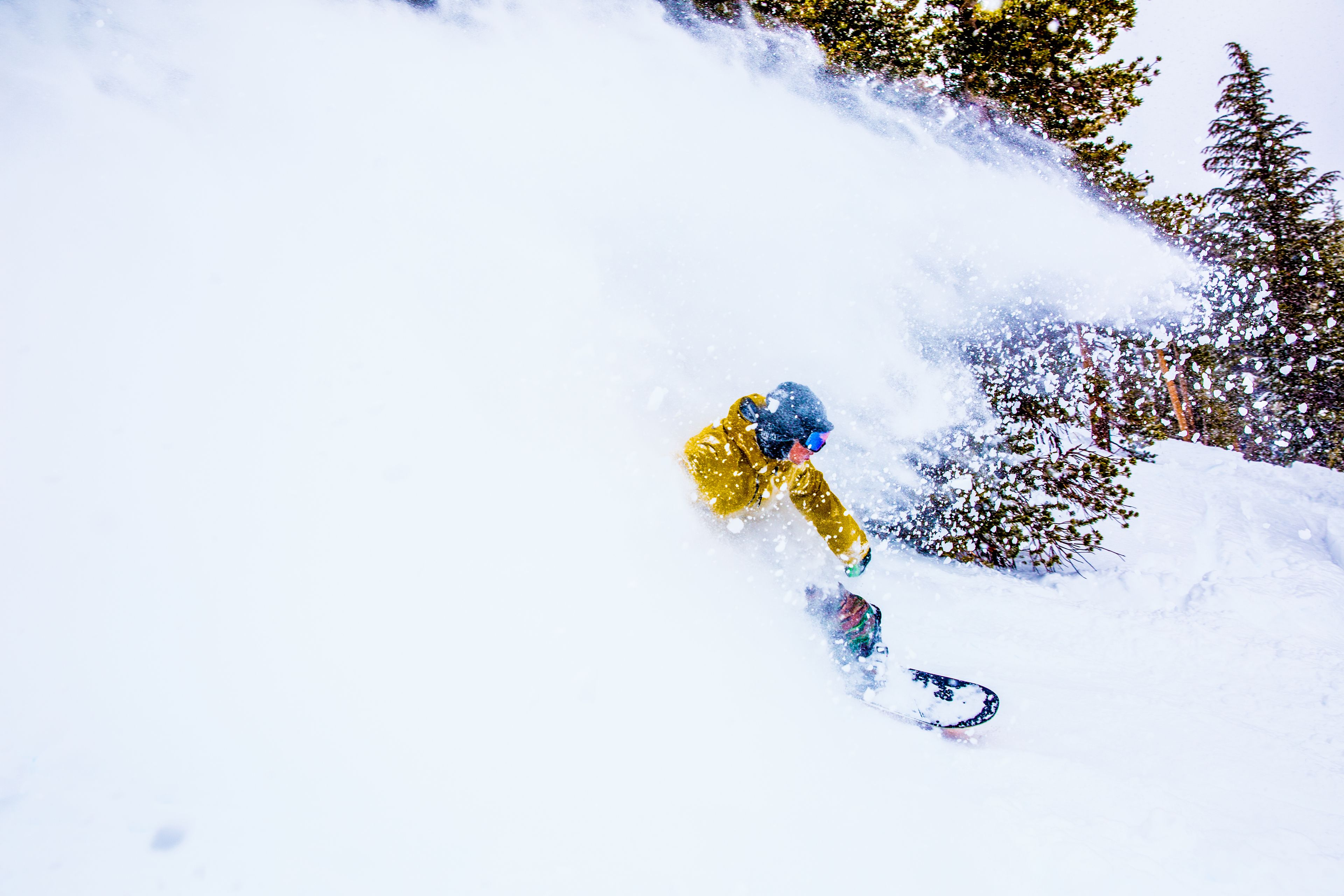 A snowboarder in a yellow jacket navigating a snowy slope.