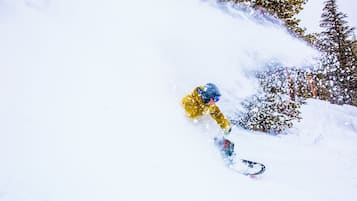 A snowboarder in a yellow jacket navigating a snowy slope.