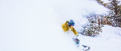 A snowboarder in a yellow jacket navigating a snowy slope.