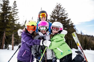Eine Gruppe von Personen in Winterkleidung mit Skiern und Stöcken steht in einem verschneiten Wald.