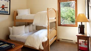 A bunk bed room with a window, a desk with a lamp, and a framed picture on the wall.