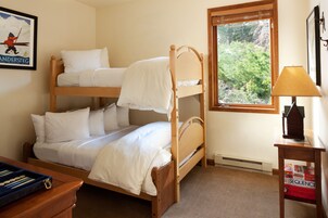 Camera con letto a castello, una finestra, una scrivania con lampada e un quadro appeso al muro.