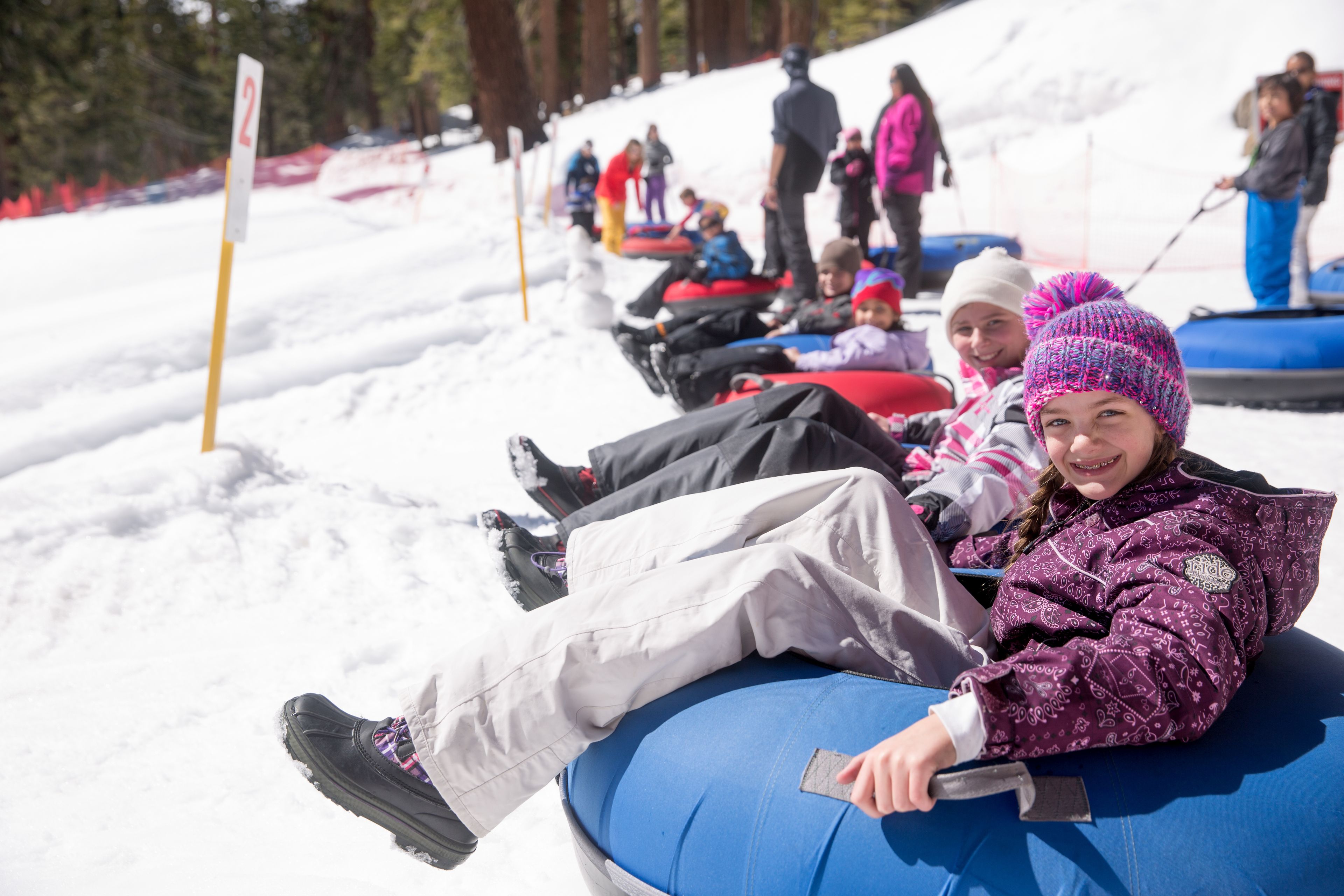 A group of people sledding on snow tubes on a snowy slope.