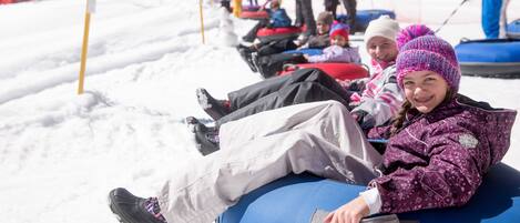 A group of people sledding on snow tubes on a snowy slope.