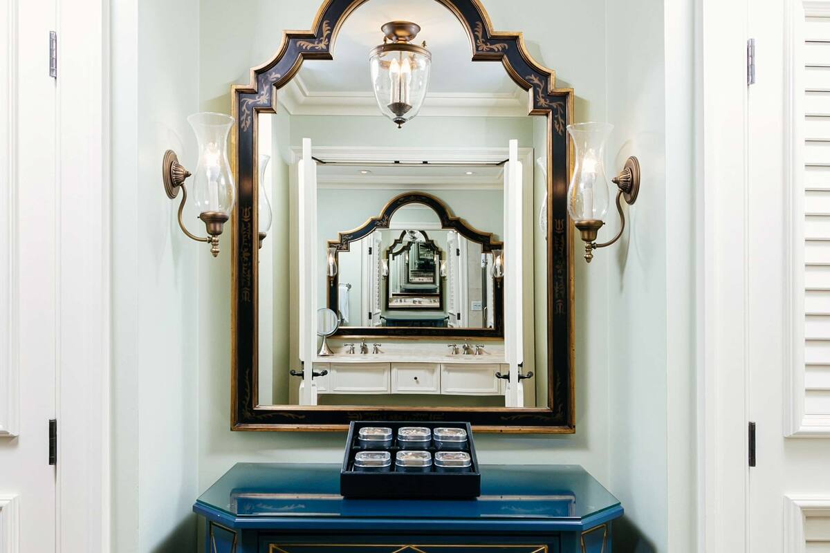 A corner with a blue dresser, a mirror, and wall sconces.