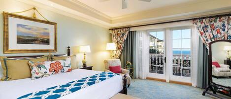 Une chambre d’hôtel avec un grand lit, un ventilateur de plafond, un balcon avec vue et un tableau au mur.