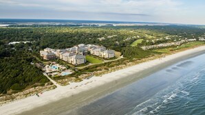 Vista aérea de um resort costeiro com vários edifícios, uma praia e um campo de golfe.