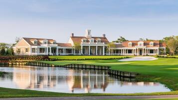 A large, elegant building with a central pavilion, a pond, and a well-manicured lawn.