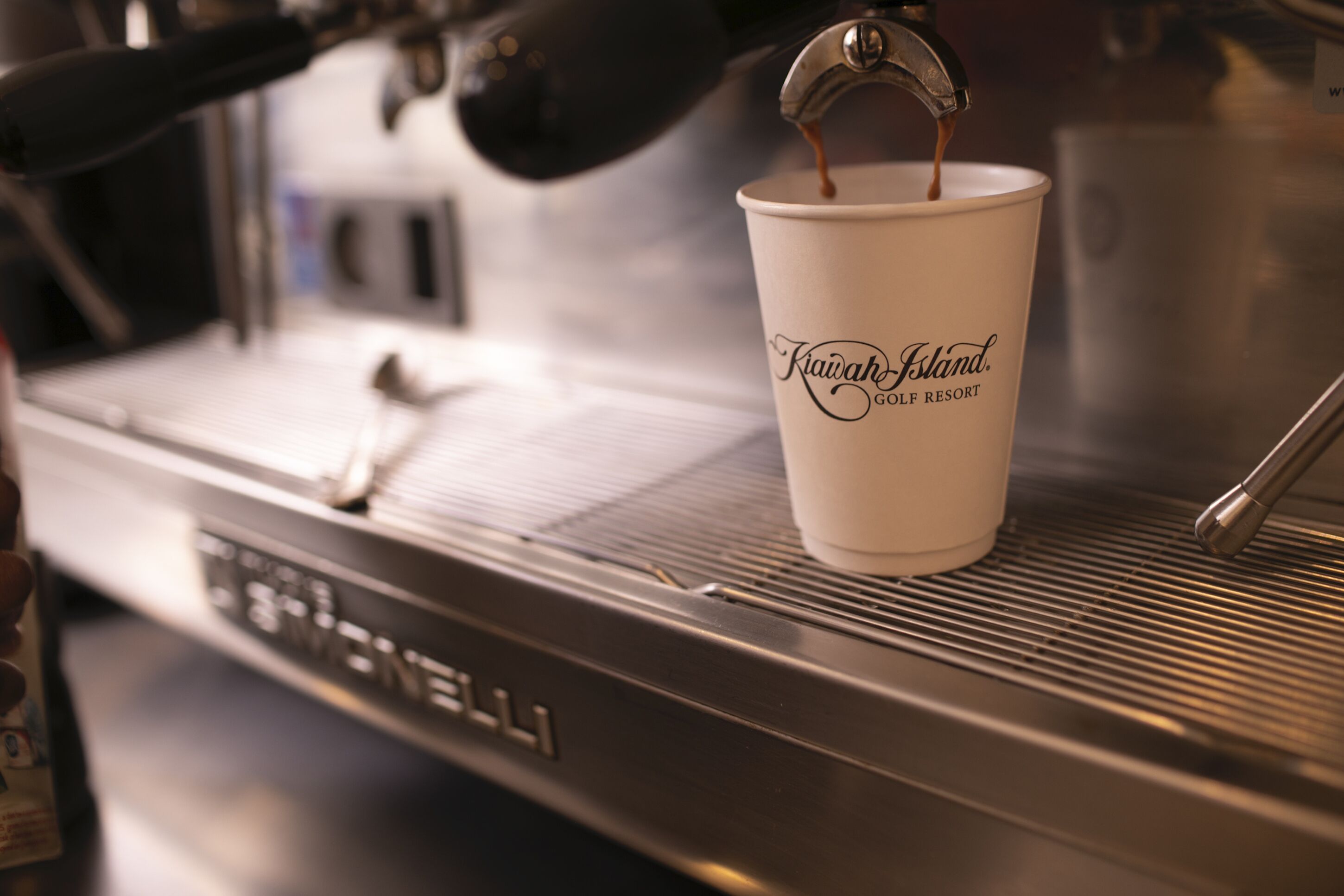 A coffee cup labeled "Kiawah Island Golf Resort" on a coffee machine.