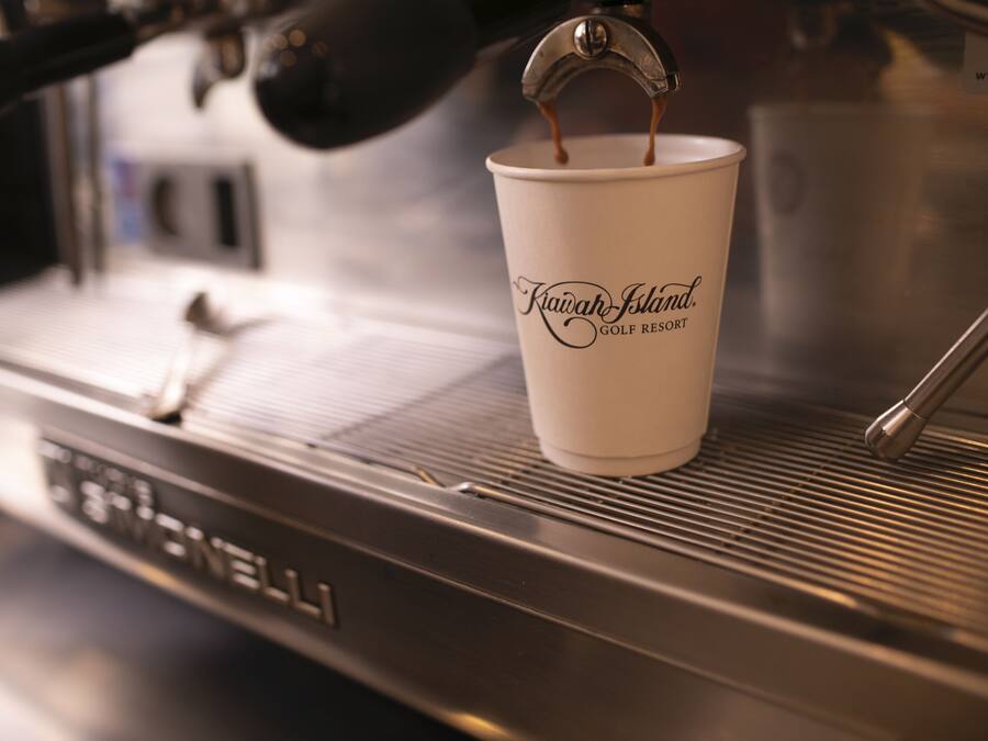 A coffee cup labeled "Kiawah Island Golf Resort" on a coffee machine.