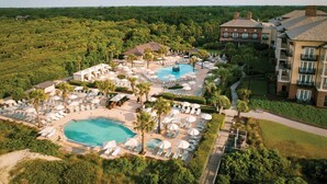 Resort com várias piscinas, espreguiçadeiras e um edifício grande com varandas.