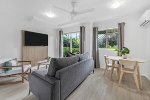 Una sala de estar moderna con un sofá gris, una mesa de centro de madera y una mesa de comedor con sillas.