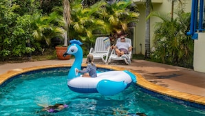 A swimming pool with a blue and white swan float. - Mackay Seabreeze Apartments (Slade Point)