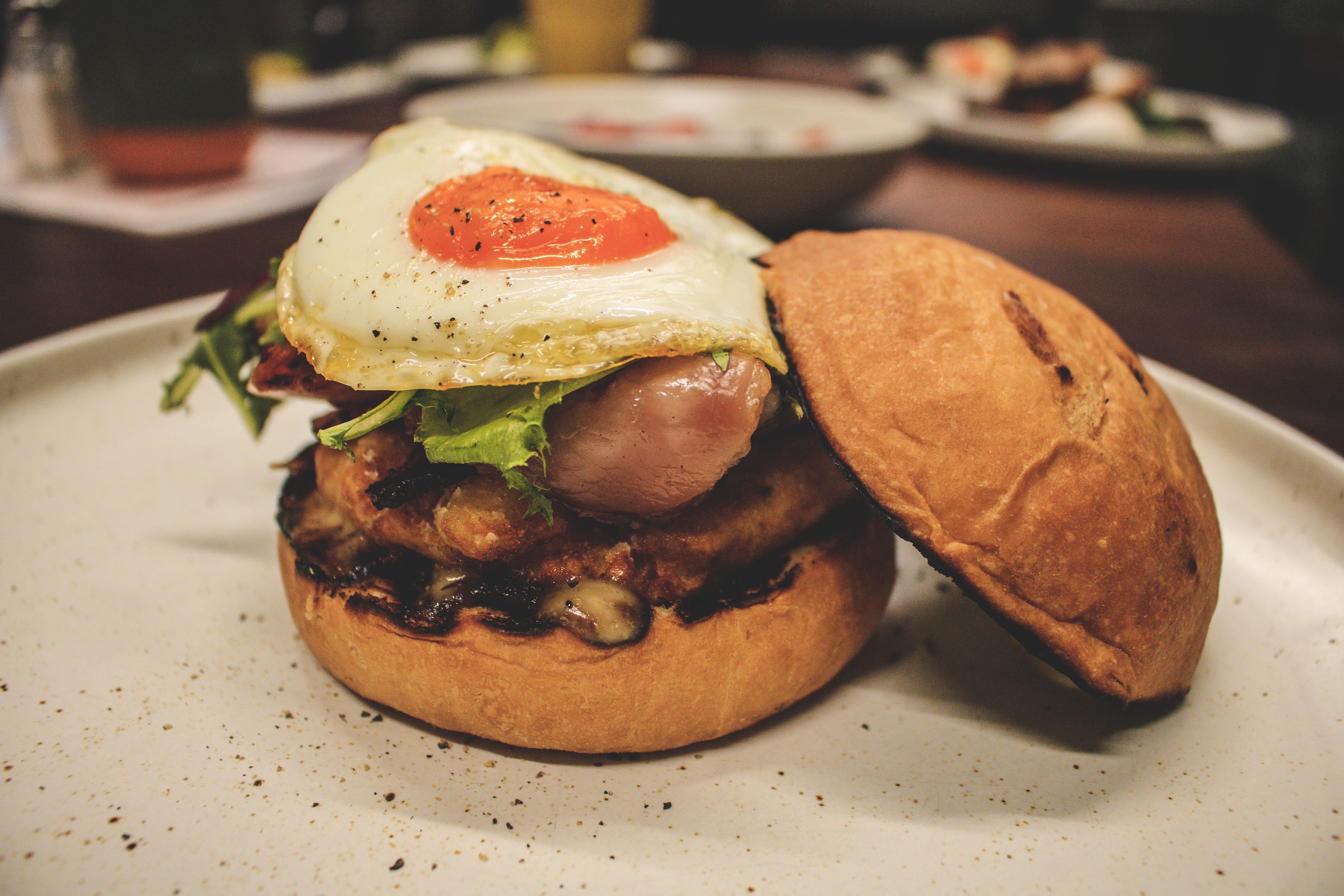 Un sándwich con un huevo frito encima, sobre un plato.